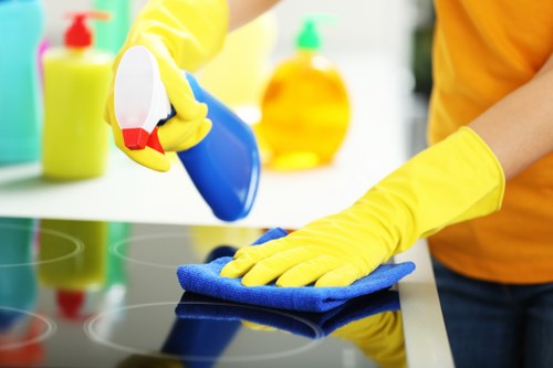 Technician cleaning an oven in Finchley with safety equipment