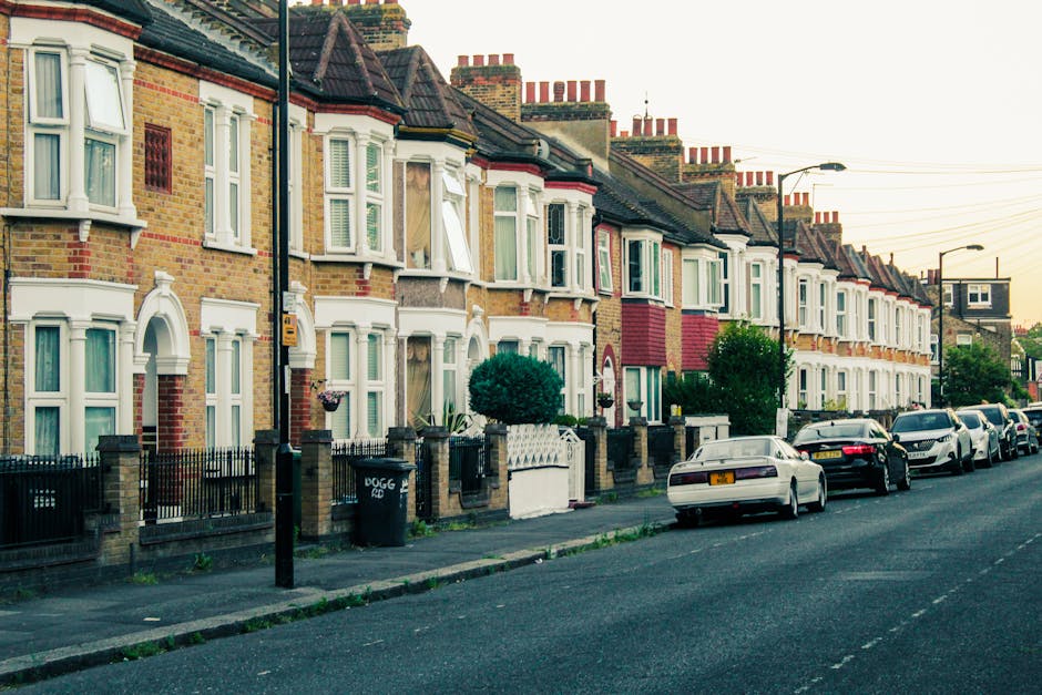 A row of Victorian terraced houses with brick facades and white bay windows lining a quiet street in East Finchley during the daytime. The houses feature ornamental white trims around the windows and