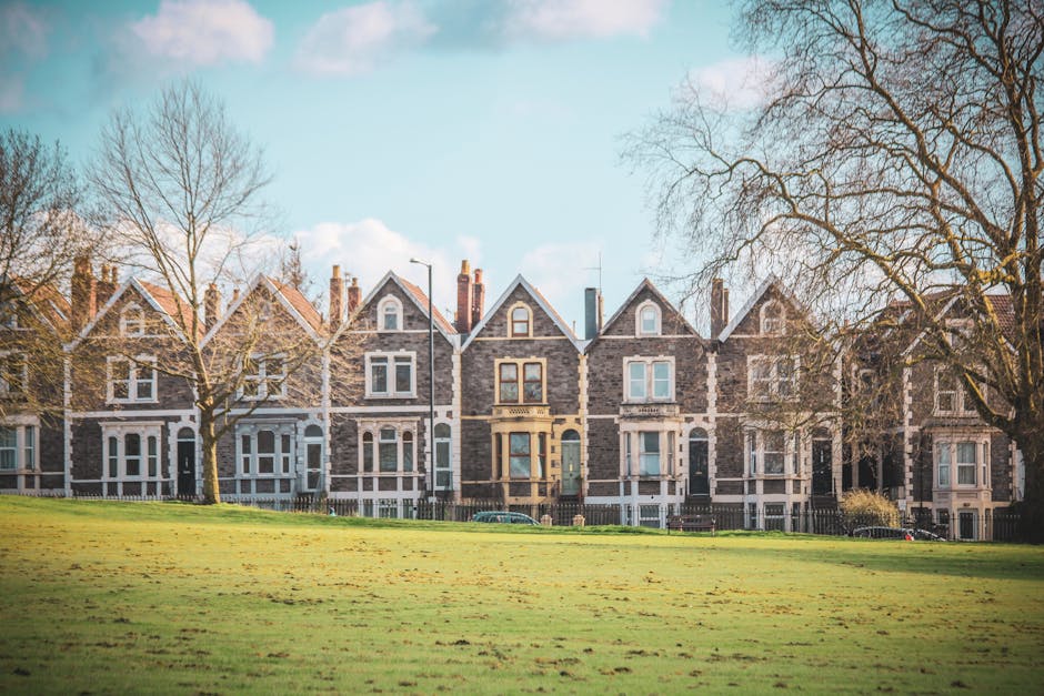 A row of Victorian terraced houses with brick facades and white bay windows lining a quiet street in East Finchley during the daytime. The houses feature ornamental white trims around the windows and
